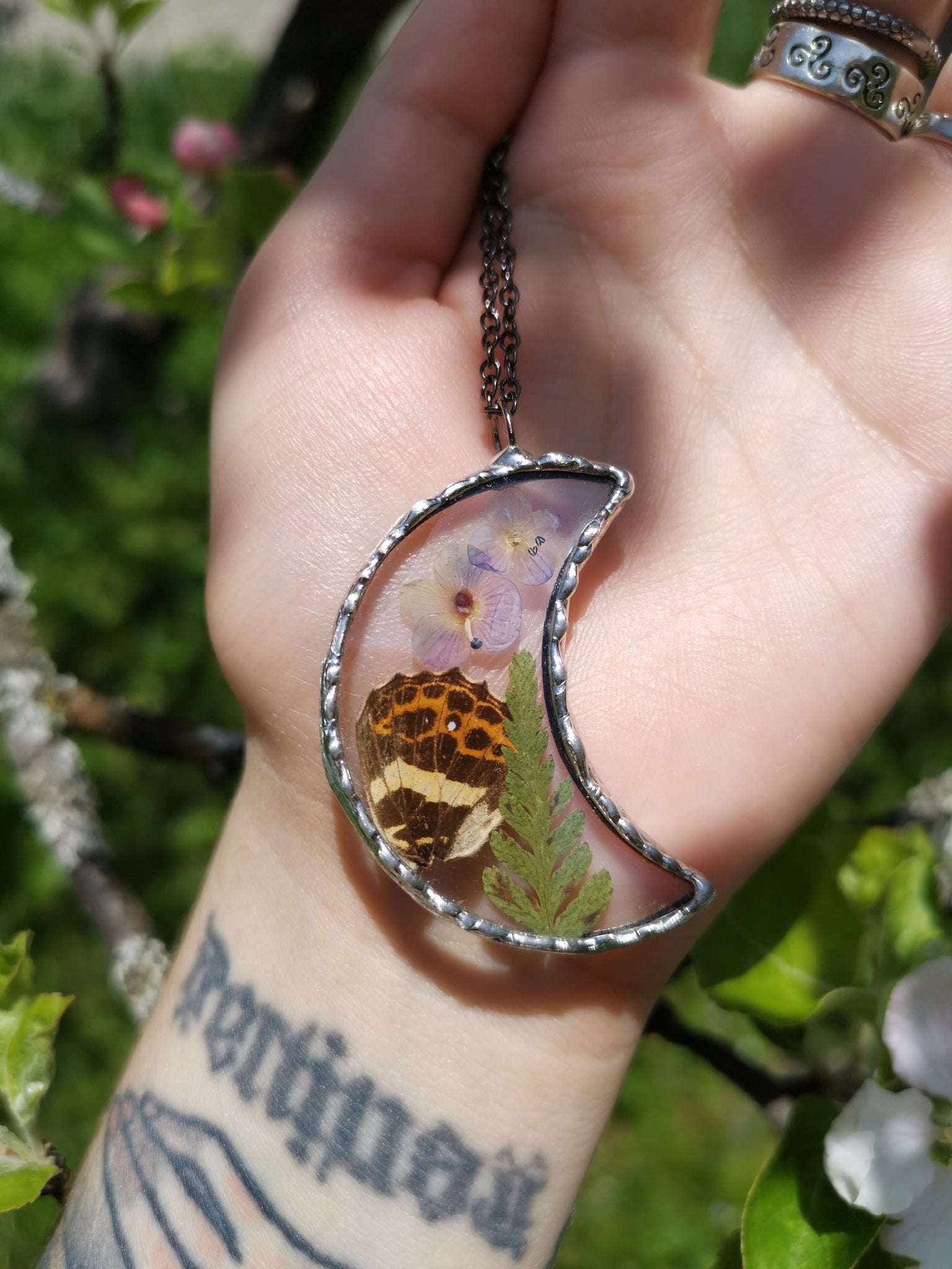 Glass moon pendant with butterfly wing and dried plants